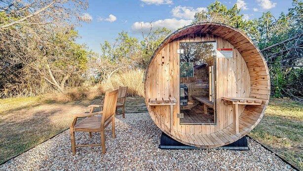 A wooden cabin with a circular design, a bench outside, and a gravel path. - Suniland W/pool, Hot-tub and Sauna! (Fredericksburg)