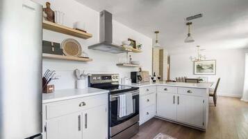 Une cuisine moderne avec des armoires blanches, des appareils en acier inoxydable et des étagères en bois.
