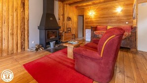 A cozy room with a fireplace, wooden walls, a red sofa, and a wooden floor.