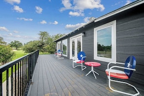 A wooden deck with outdoor seating and a view of a green landscape. - Charming Farmhouse W/hot-tub Near 290 Wine Trail (Fredericksburg)