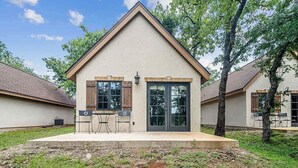 A single-story house with a gabled roof, a front porch with two chairs, and a small table. - The Manor Haus at Messina Hof Hill Country Winery-presidents (Fredericksburg)