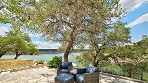 A patio with wicker furniture and a view of a lake. - Luxury Lakefront Escape on Lake Travis (Marble Falls)
