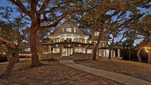 A large, multi-story house with a prominent front porch and a covered walkway leading to the entrance. - Luxury Lakefront Escape on Lake Travis (Marble Falls)