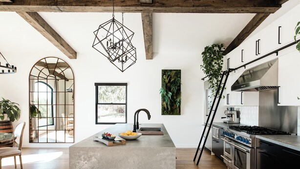 Una cocina moderna con una isla de hormigón, electrodomésticos de acero inoxidable y un amplio ventanal que proporciona luz natural.