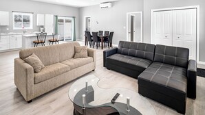 Un salon moderne avec un canapé beige, un canapé en cuir noir et une table basse en verre.