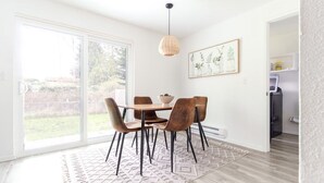En matplats med ett bord och stolar, en hängande lampa och ett inramat konstverk på väggen.
