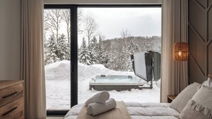 A bedroom with a large window, a bed, a wooden dresser, and a hot tub outside. - Chalet Symbiose21 - Spa& Sauna& Ski (Saint-Come)