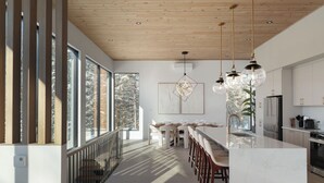 A modern kitchen with a large island, pendant lights, and a view of trees through large windows. - Chalet Symbiose21 - Spa& Sauna& Ski (Saint-Come)
