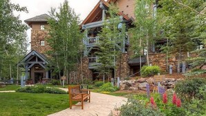 A lodge with stone and wood architecture, a stone pathway, and a bench.