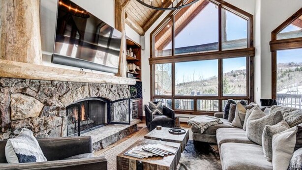 A cozy living room with a stone fireplace, large windows, and comfortable seating.