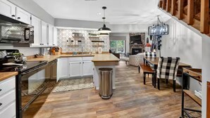 Een ruime keuken met witte kasten, een centraal eiland en een eethoek met geruit tafelkleed.