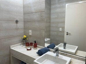 A bathroom with two sinks, a mirror, and a toilet. - Apartment with an ocean view in Maceió (Maceió)