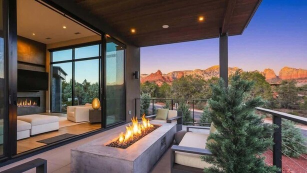 A modern outdoor living area with a fire feature, seating, and a view of red rock formations.
