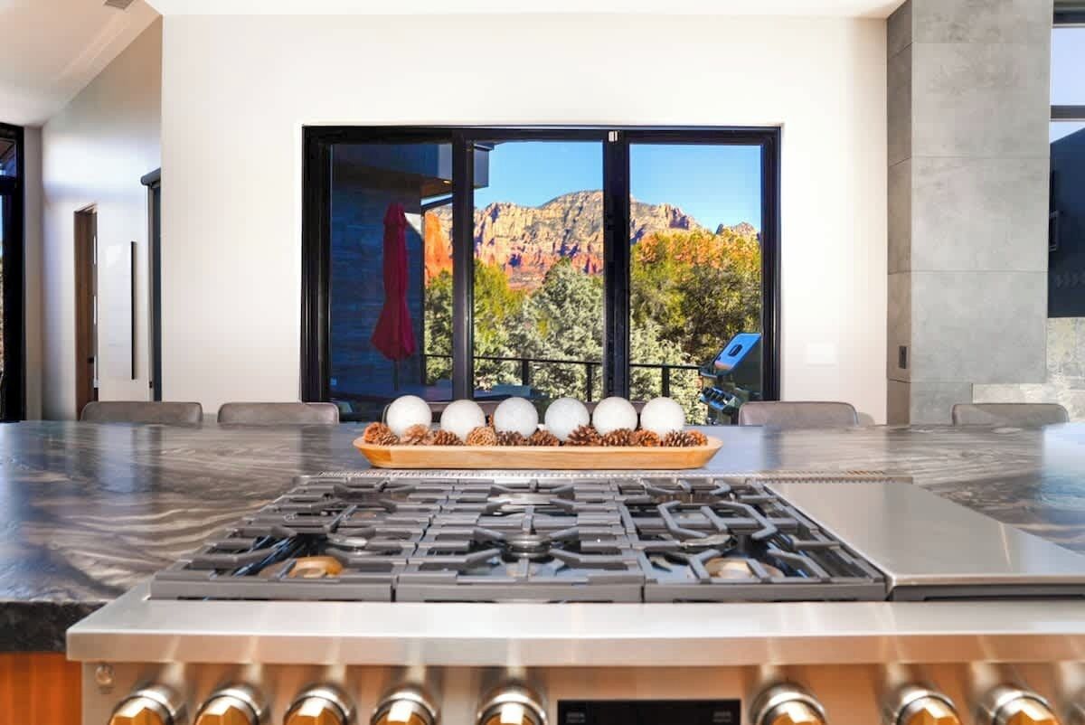A kitchen with a gas stove, a large window with a mountain view, and a wooden tray with eggs.