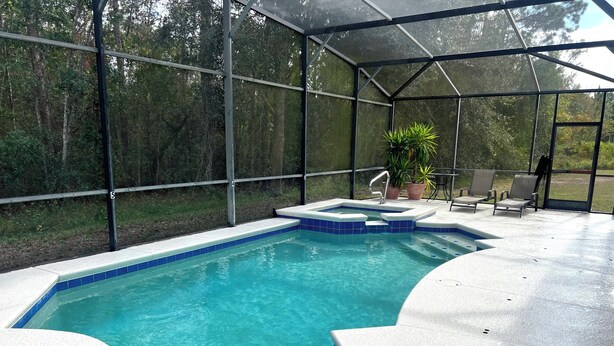 Piscina coberta com hidromassagem, cercada por um revestimento de vidro e equipada com espreguiçadeiras.