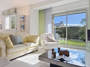 A living room with a sofa, armchair, and a glass coffee table with magazines. - Carnac – 4-room house – 100 m² – Wi-Fi (CARNAC)