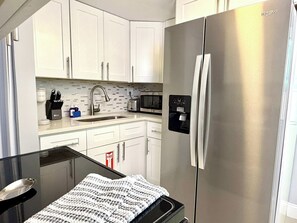 A compact kitchen with white cabinets, a stainless steel refrigerator, a microwave, and a sink. - 1 Bedroom on the Barrier Island. Walk to the Beach (Fort Lauderdale)