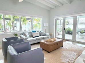 A modern living room with a grey sofa, a brown ottoman, and a grey armchair. - 2 Bedroom on the Barrier Island. Walk to the Beach (Fort Lauderdale)