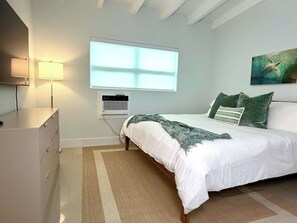 A bedroom with a bed, bedside lamp, air conditioning unit, and a painting on the wall. - 2 Bedroom on the Barrier Island. Walk to the Beach (Fort Lauderdale)