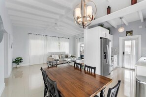 A spacious living area with a wooden dining table, a sofa, and a kitchen in the background. - 2 Bedroom on the Barrier Island. Walk to the Beach (Fort Lauderdale)