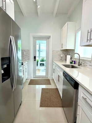 A modern kitchen with stainless steel appliances, white cabinetry, and a view to the outside. - 2 Bedroom on the Barrier Island. Walk to the Beach (Fort Lauderdale)