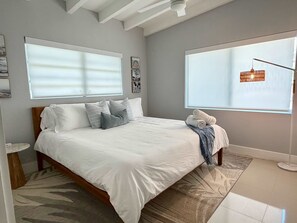 A bedroom with a bed, a nightstand, a window with blinds, and a floor lamp. - 3 Bedroom on the Barrier Island. Walk to the Beach (Fort Lauderdale)