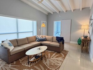 Ein modernes Wohnzimmer mit einem Ecksofa, einem Couchtisch und einem großen Fenster.
