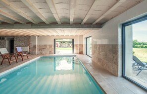 Une piscine avec un mur en pierre et une vue sur l’extérieur.
