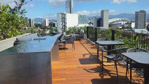 Una terraza en la azotea con mobiliario exterior, piscina y vistas a la ciudad.