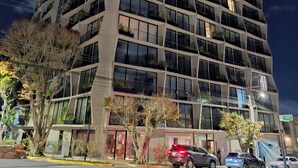 Un edificio de varios pisos con un diseño arquitectónico moderno, que cuenta con balcones con vegetación.