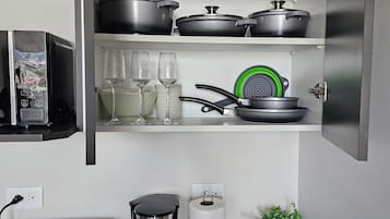 A kitchen with a toaster, coffee maker, and pots on shelves.