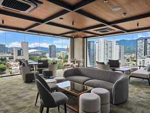 Una habitación de hotel moderna con un gran ventanal, asientos cómodos y vistas a la ciudad.