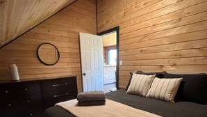 A bedroom with a bed, a dresser, and a circular mirror on the wall. - Meadow Ridge Apartment — Minutes to Salmon River (Altmar)