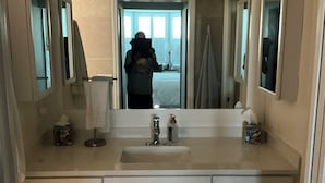A bathroom with a large mirror, a sink, and cabinets. - Florida Condo for Monthly rental Gated Golf Community available MarchApril 2026. (Fort Myers)