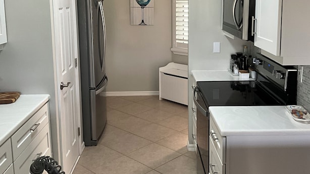 A modern kitchen with white cabinetry, a stainless steel refrigerator, a built-in oven, and a microwave. - Florida Condo for Monthly rental Gated Golf Community available MarchApril 2026. (Fort Myers)