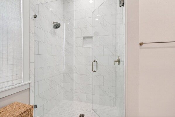 Box de vidro com azulejos de mármore branco, porta de vidro e porta-toalhas.