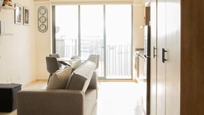 Et moderne soveværelse med en stor seng, en sofa, et spiseområde og udsigt over byen.