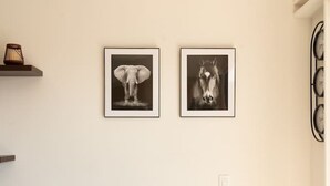 Et rundt spisebord med en marmortop, to indrammede sort-hvide fotografier og en lille sort genstand på bordet.