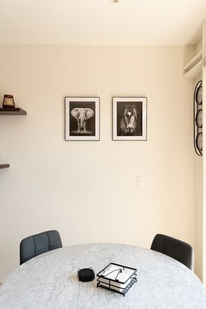 A round dining table with a marble top, two framed black and white photographs, and a small black object on the table. - Myla - Loft 10 - in Chapultepec - HighF (Mexico City)