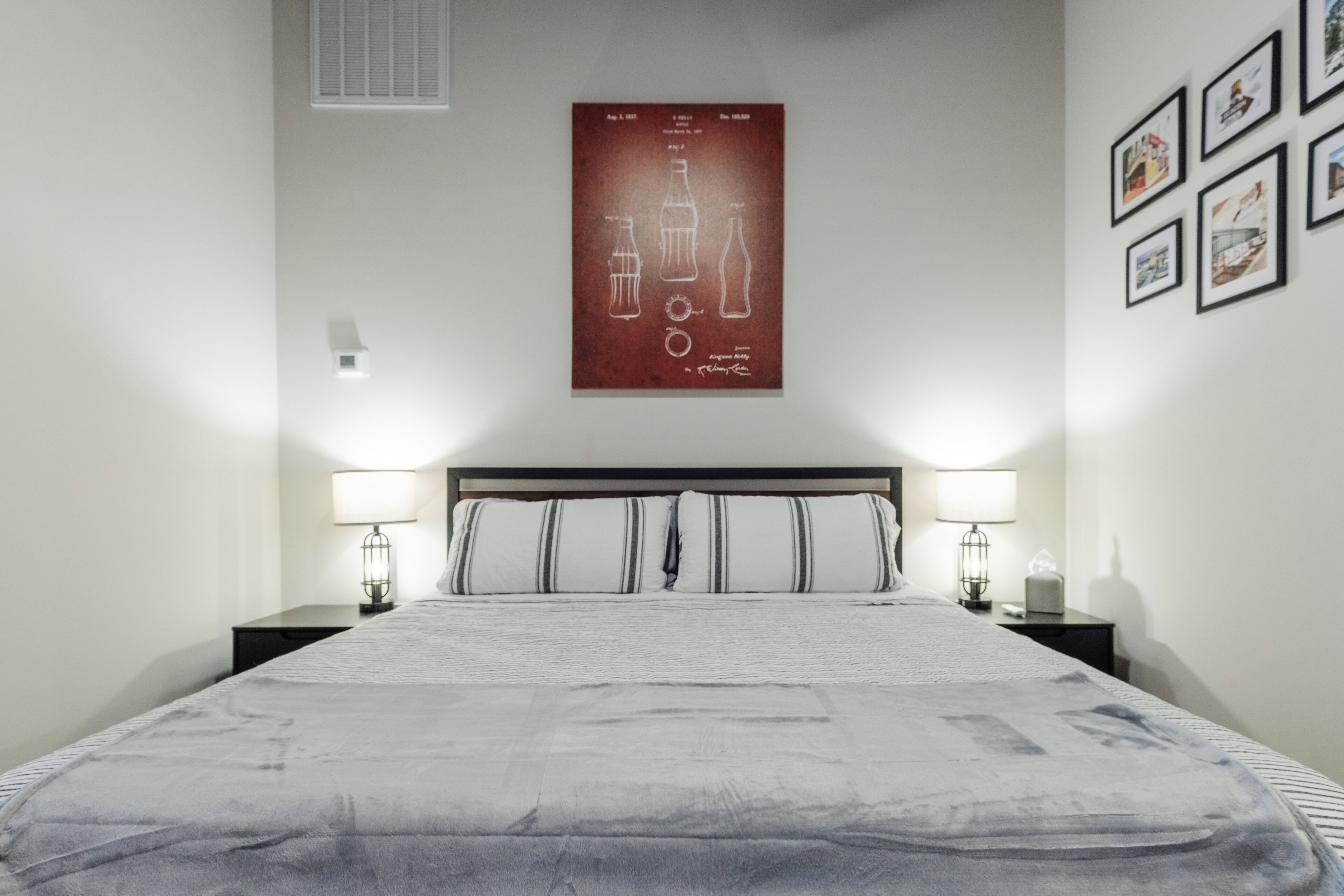 A neatly arranged bedroom with a large bed, two bedside tables with lamps, and a poster on the wall.