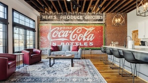 A modern kitchen with a large Coca-Cola mural, wooden beams, and a bar area.