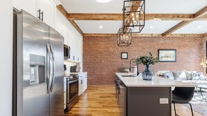 Una cocina moderna con refrigerador de acero inoxidable, piso de madera y pared de ladrillo.