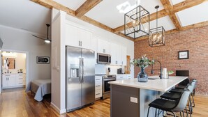 Una cocina moderna con armarios blancos, electrodomésticos de acero inoxidable y una isla central con taburetes de bar.
