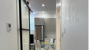 Een moderne keuken met een inbouwkoelkast, een eethoek met een glazen tafel en stoelen, en een schuifdeur van glas die leidt naar een andere kamer.