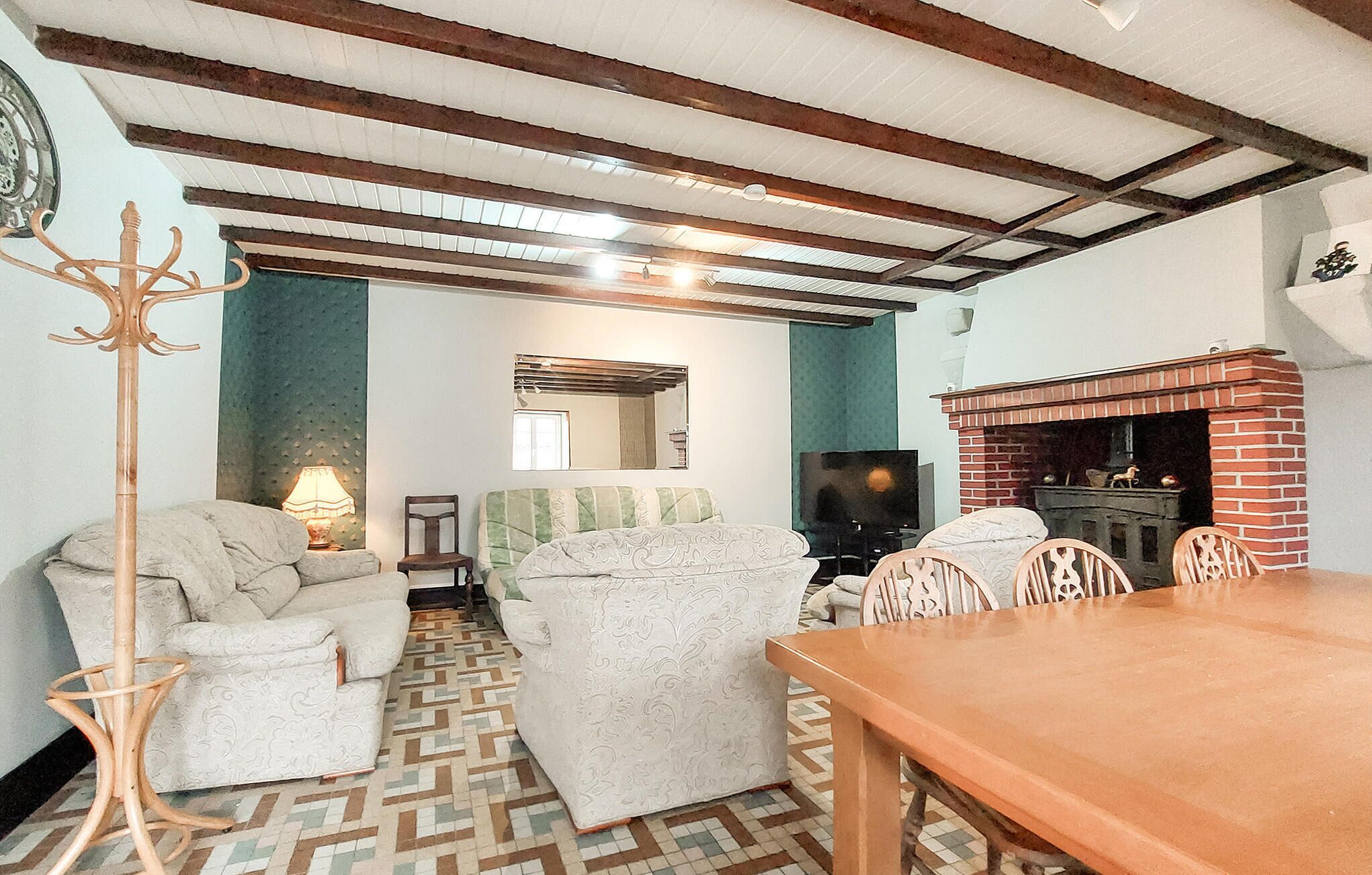 A cozy living room with a patterned floor, a wooden table, a sofa, a TV, and a fireplace.