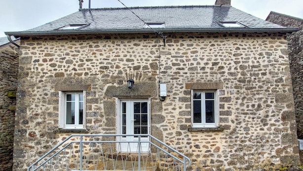 A stone building with a small porch and a metal railing.