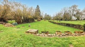 A well-maintained garden with a stone wall, wooden planters, and a variety of trees.