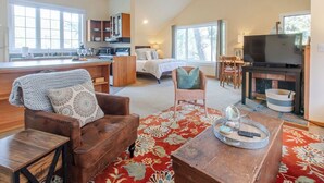 A spacious living area with a large bed, a television, and a fireplace. - Haystack Luxury - Private Studio for Monthly Stays, Near Chapman Point, Deck + BBQ (Cannon Beach)