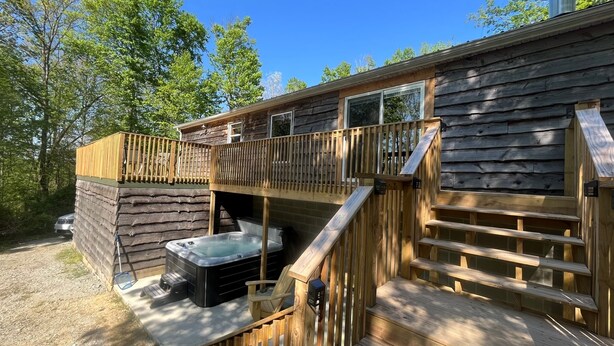 A cabin with a hot tub, wooden deck, and a covered outdoor area. - Buck Run Cottage in the heart of Hocking Hills with Wi-Fi & Spectrum TV. (Logan)