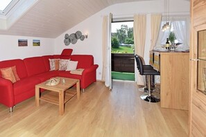 Ein gemütlicher Wohnbereich mit einem roten Sofa, einem Holztisch und einem Essbereich mit einer Bar.